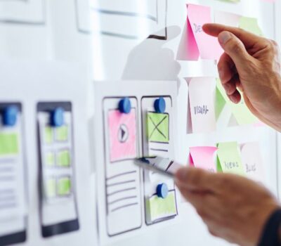 Manos trabajando en la planificación de planes de movilidad sostenible con notas adhesivas y bocetos en una pizarra.