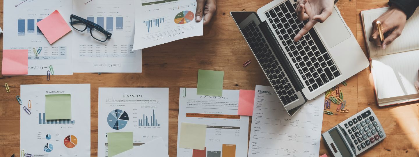 Documentos y gráficos financieros sobre una mesa durante la planificación de un plan de movilidad sostenible para empresas.